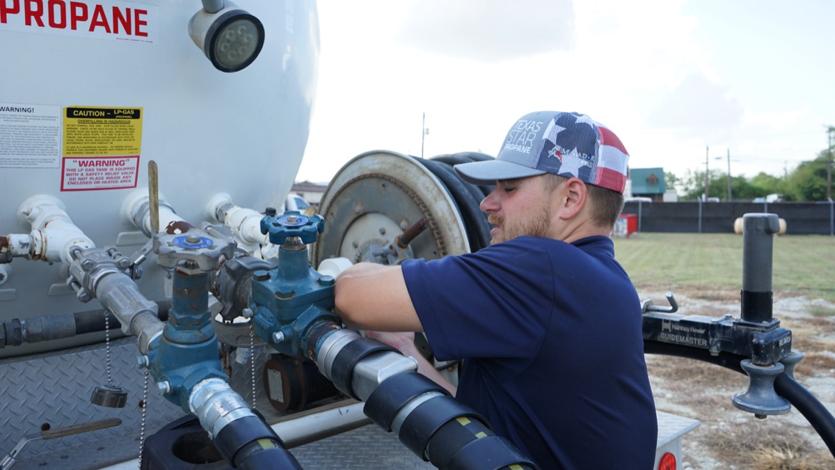 A Texas Star Propane worker connecting the hose at the valve assembly of a delivery tanker.