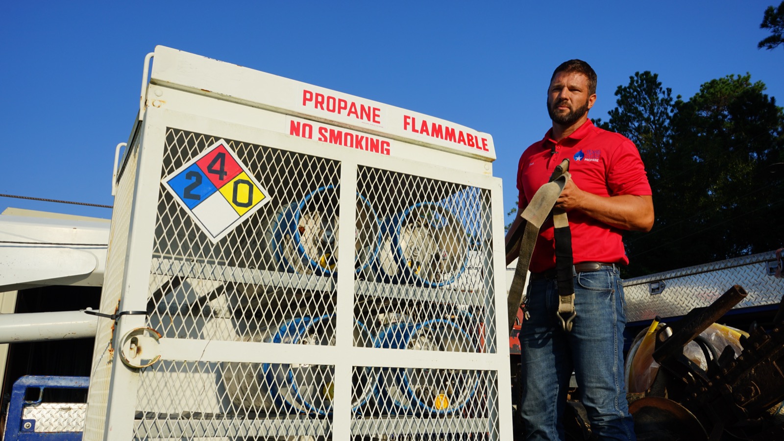 A Texas Star Propane technician beside a cylinder cage at the yard.