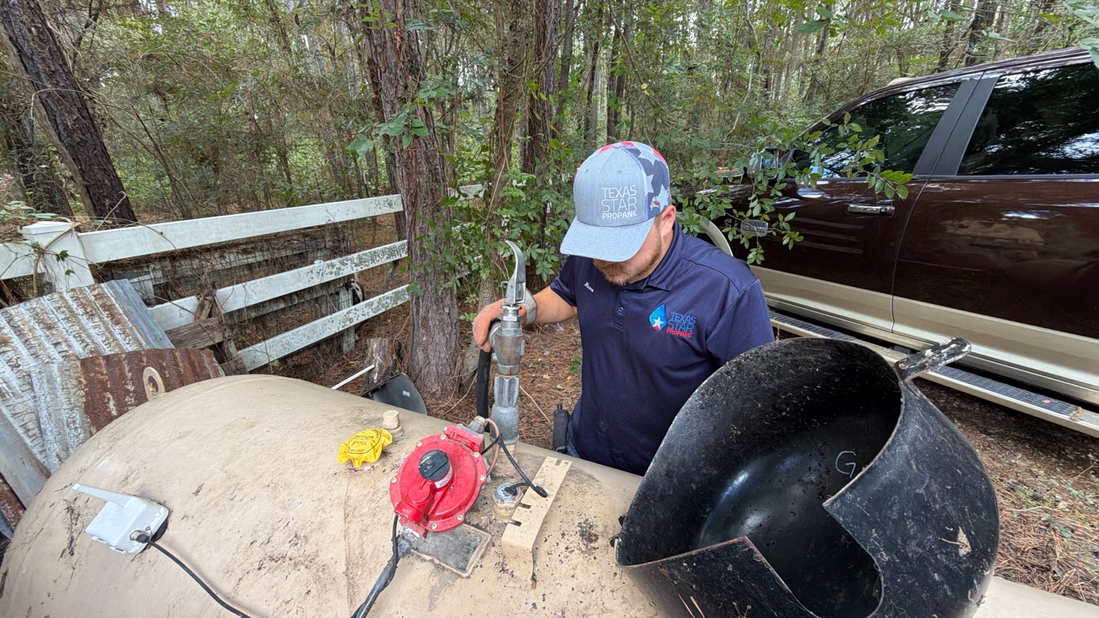 Technician servicing propane tank with branded shirt visible.