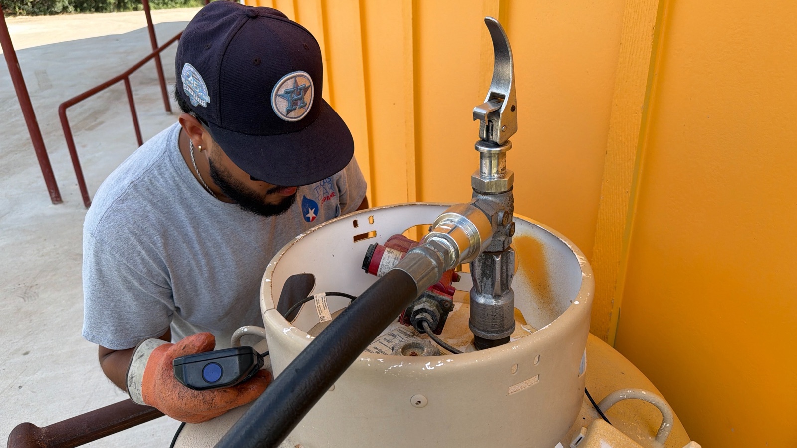 A technician filling a propane tank, hose and gauge in view.