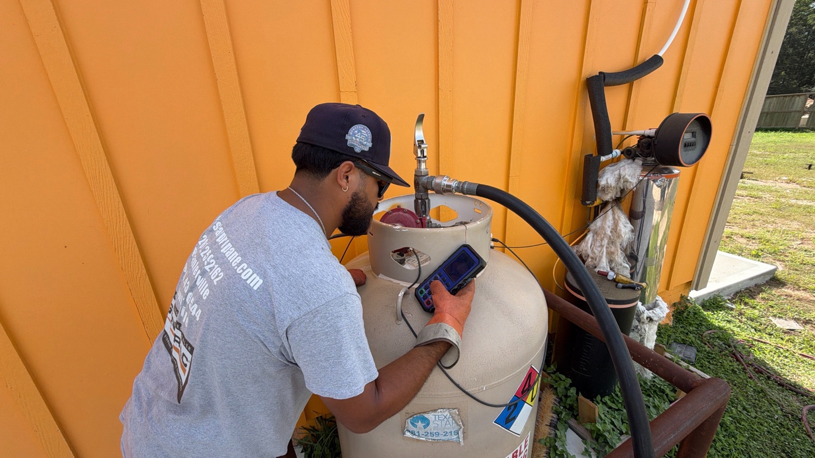 A technician in a branded shirt filling a propane tank.