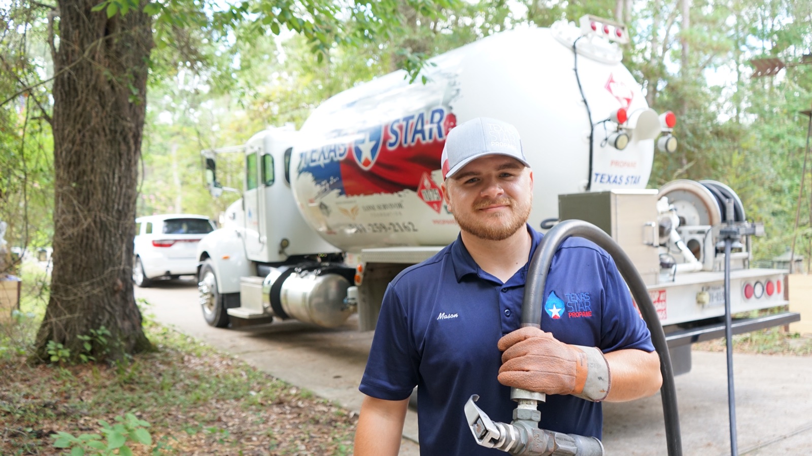 Friendly driver portrait holding nozzle with branded truck behind.