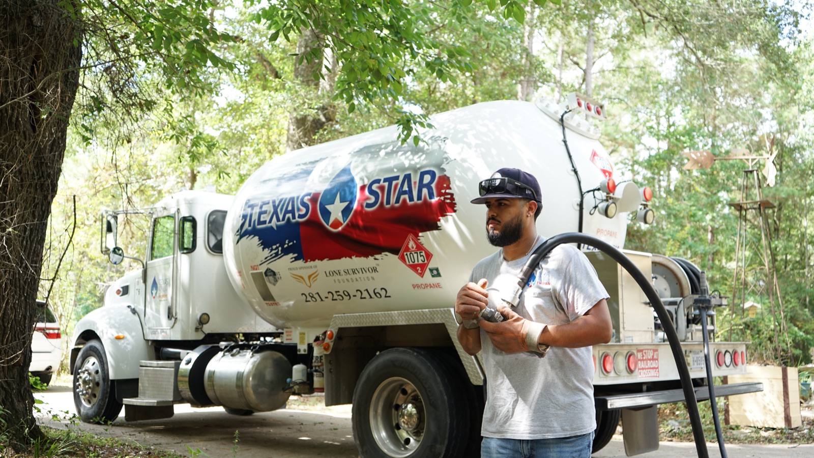 A Texas Star driver with a delivery hose beside a branded truck.