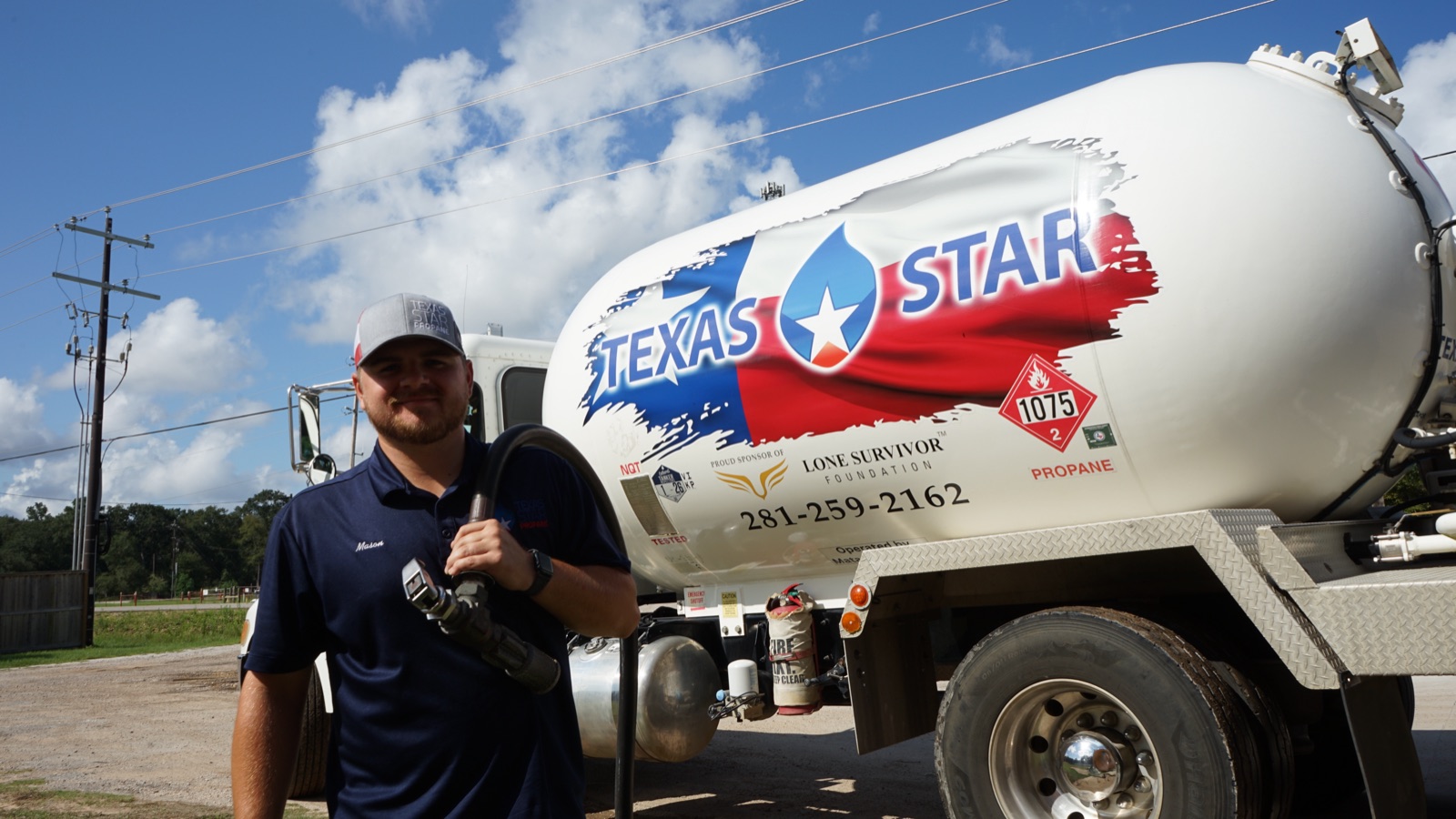 A Texas Star driver holding a delivery nozzle beside a branded truck.