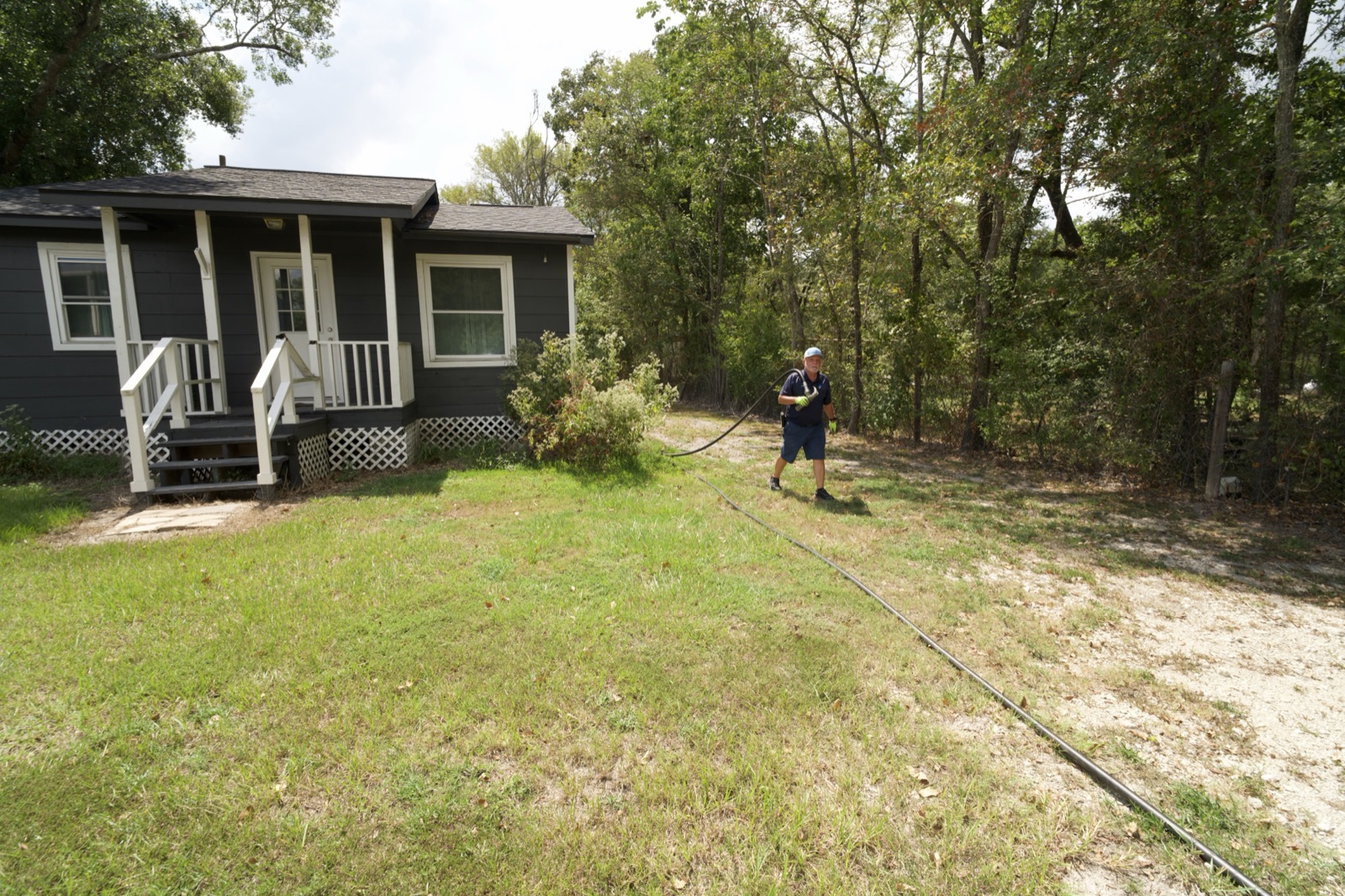 Delivery hose being pulled across a residential yard toward the house.