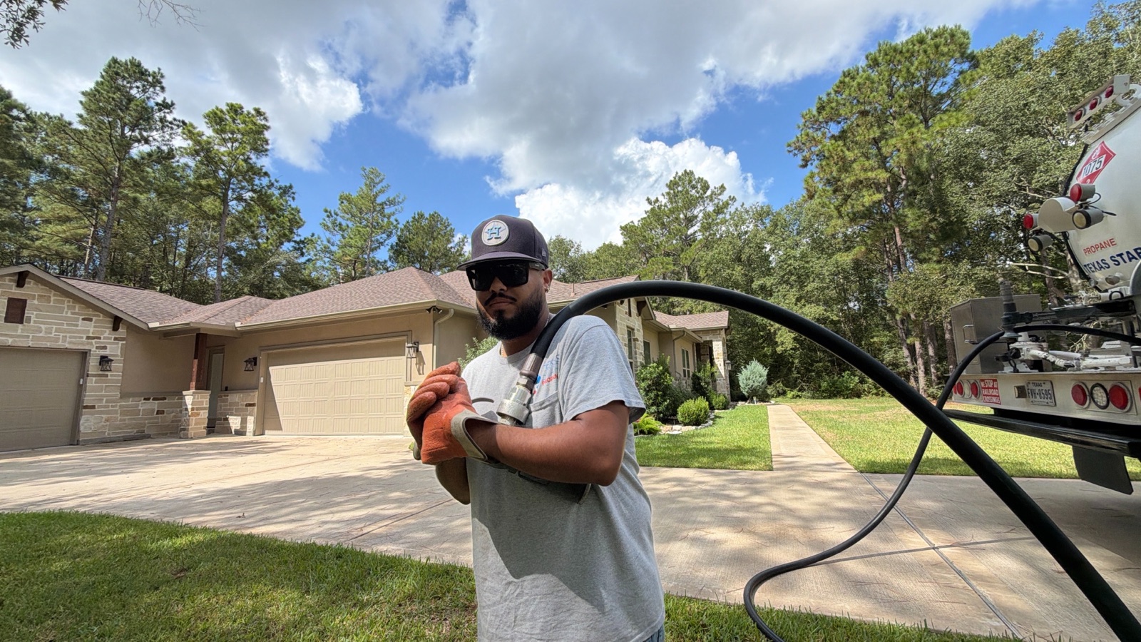 A Texas Star Propane driver with a delivery hose beside a branded truck in a residential driveway.