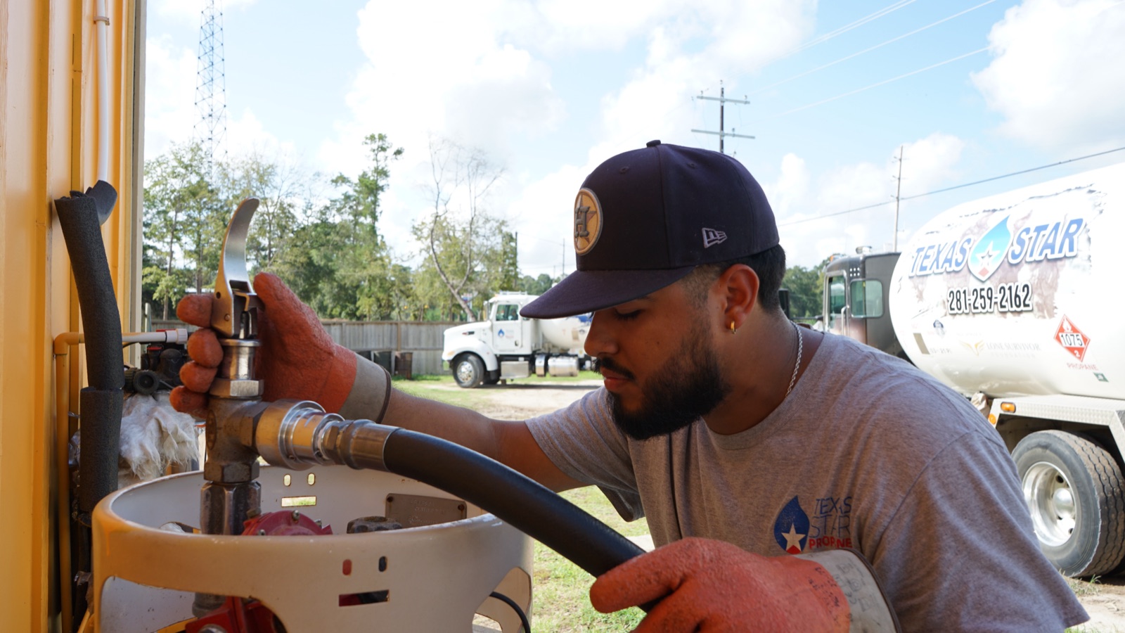 A driver filling a propane tank with a branded company truck behind.
