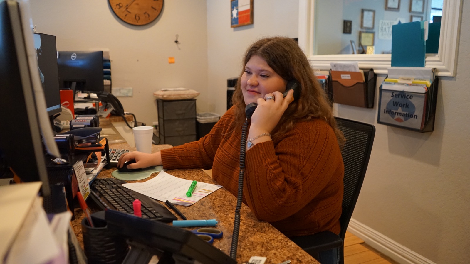 Friendly candid of office staff on the phone at her desk.