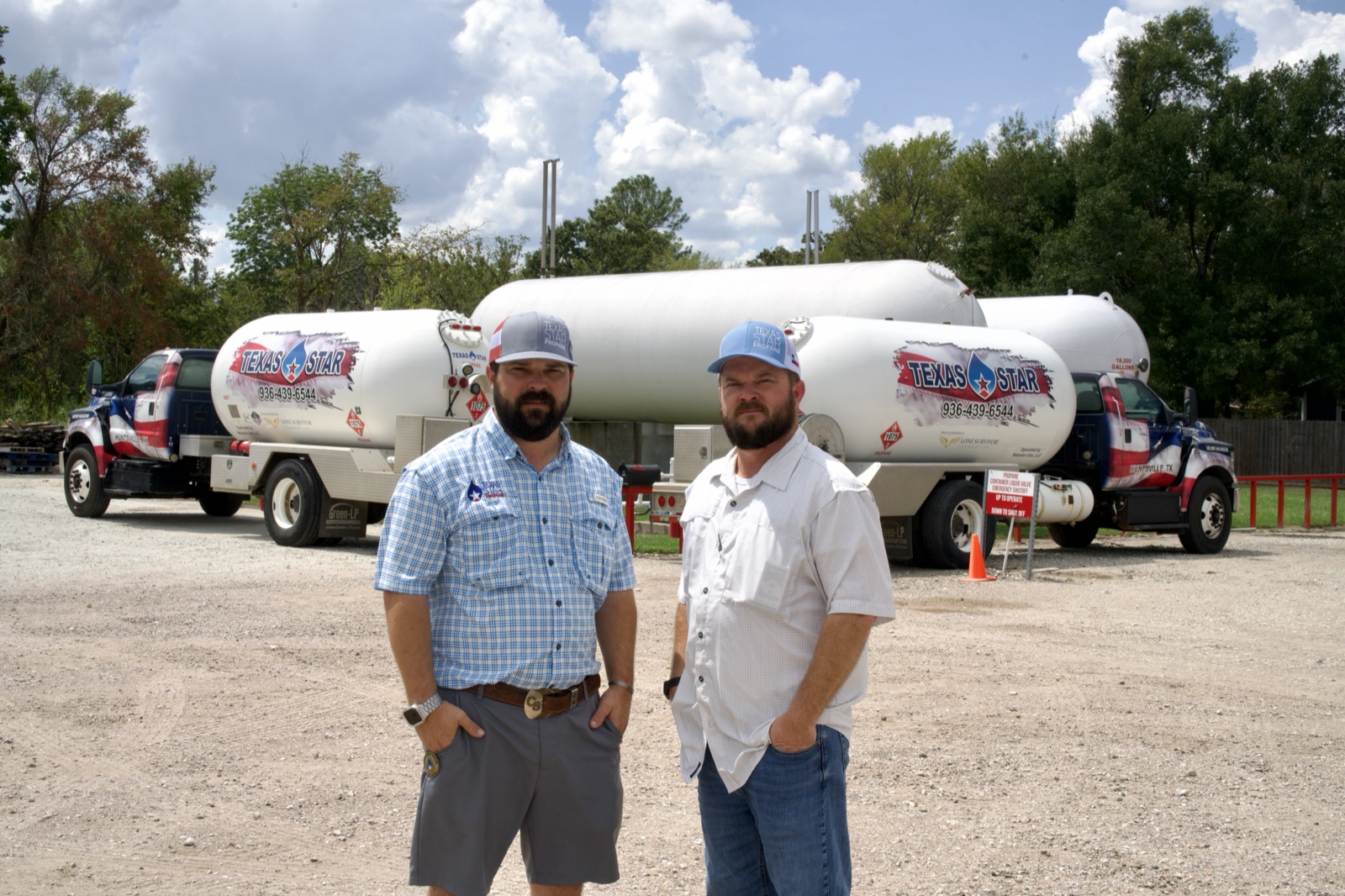 Two staff members posed confidently in front of branded propane trucks and tanks.