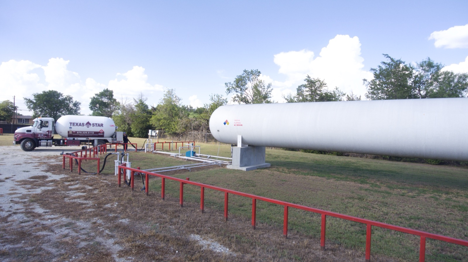 A Texas Star tanker truck connected to a large propane storage tank at a bulk plant.