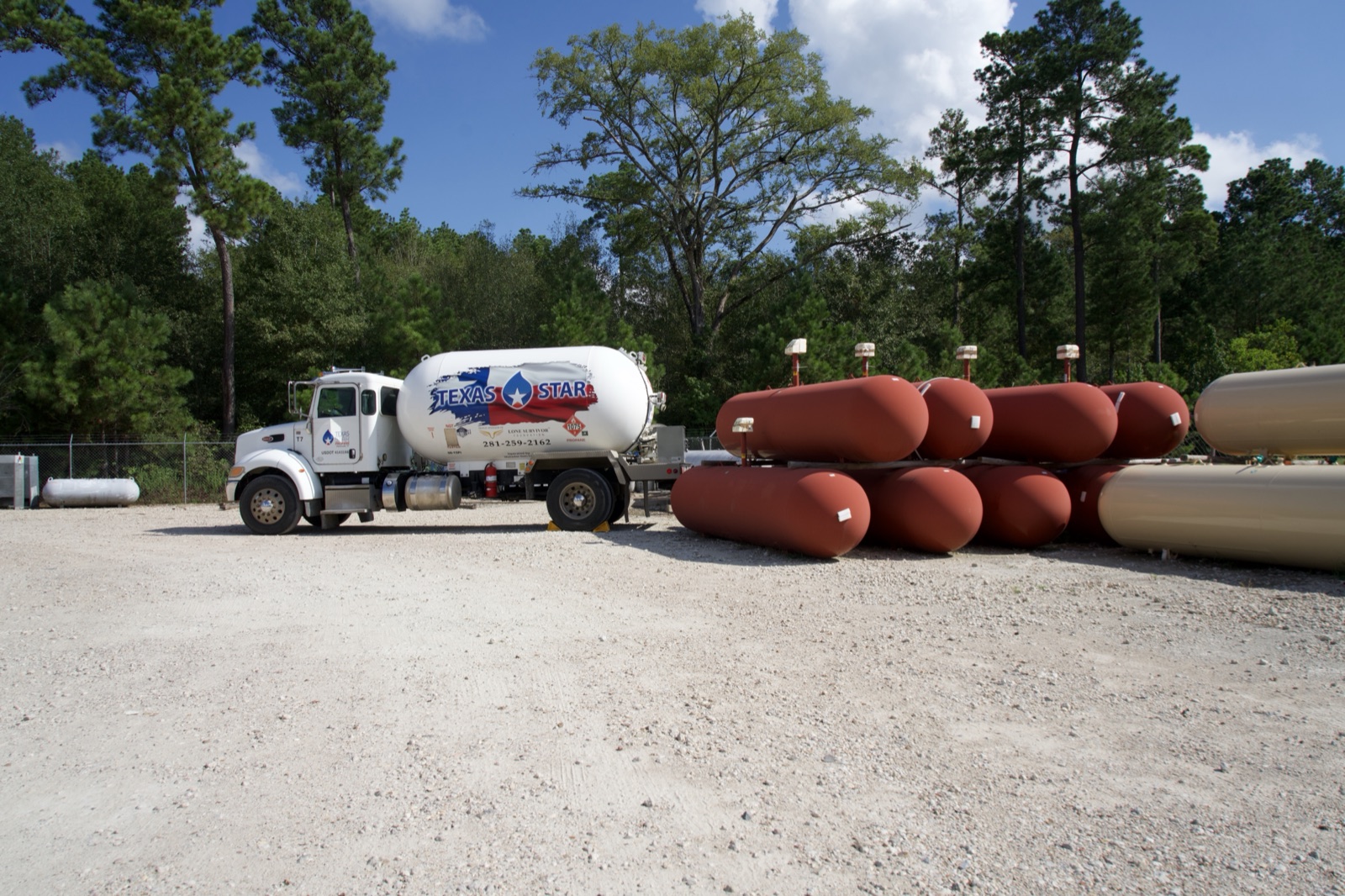 A branded delivery truck alongside stacked propane tanks.