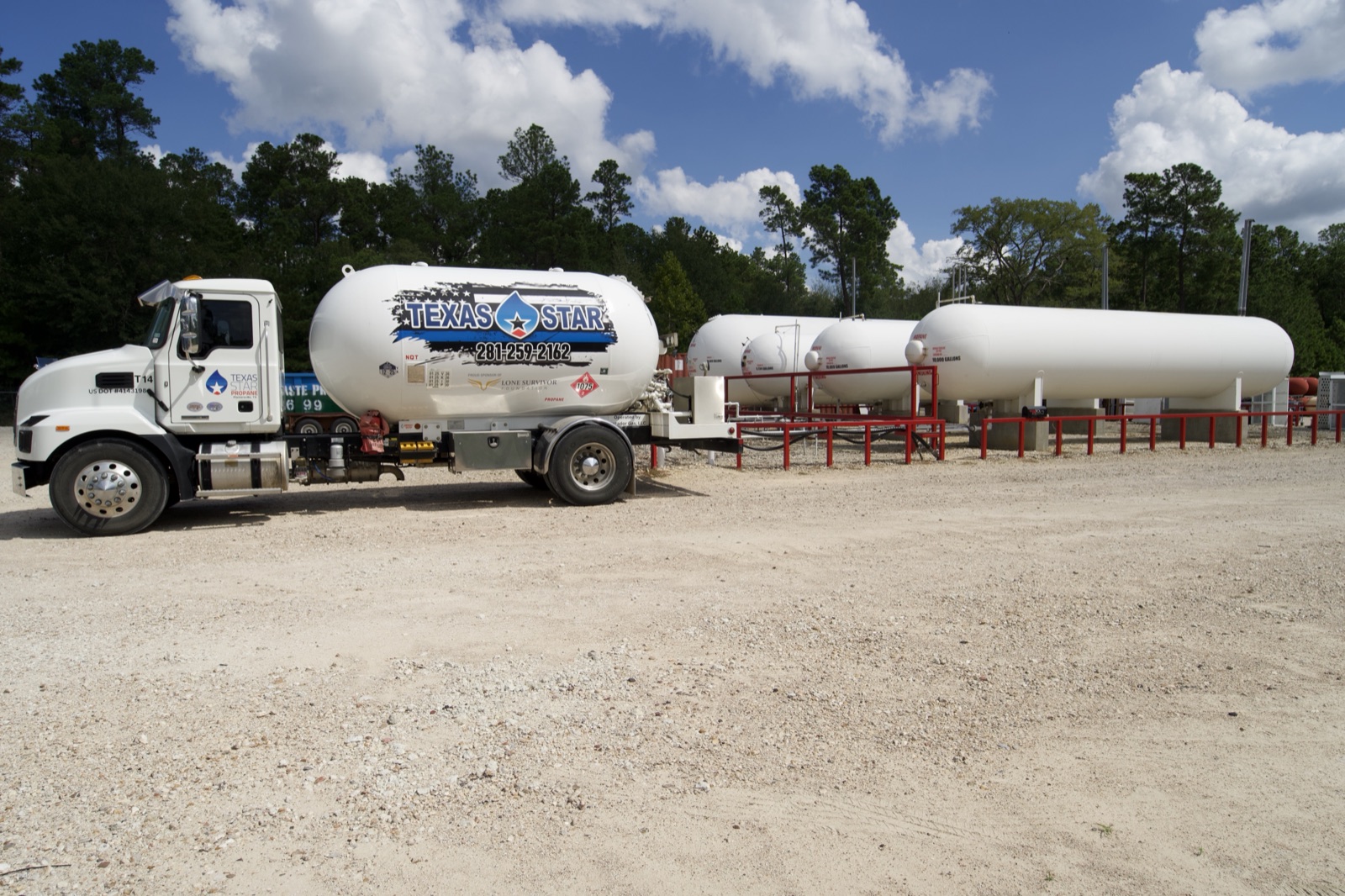 A branded Texas Star delivery truck with bulk plant storage tanks behind it.